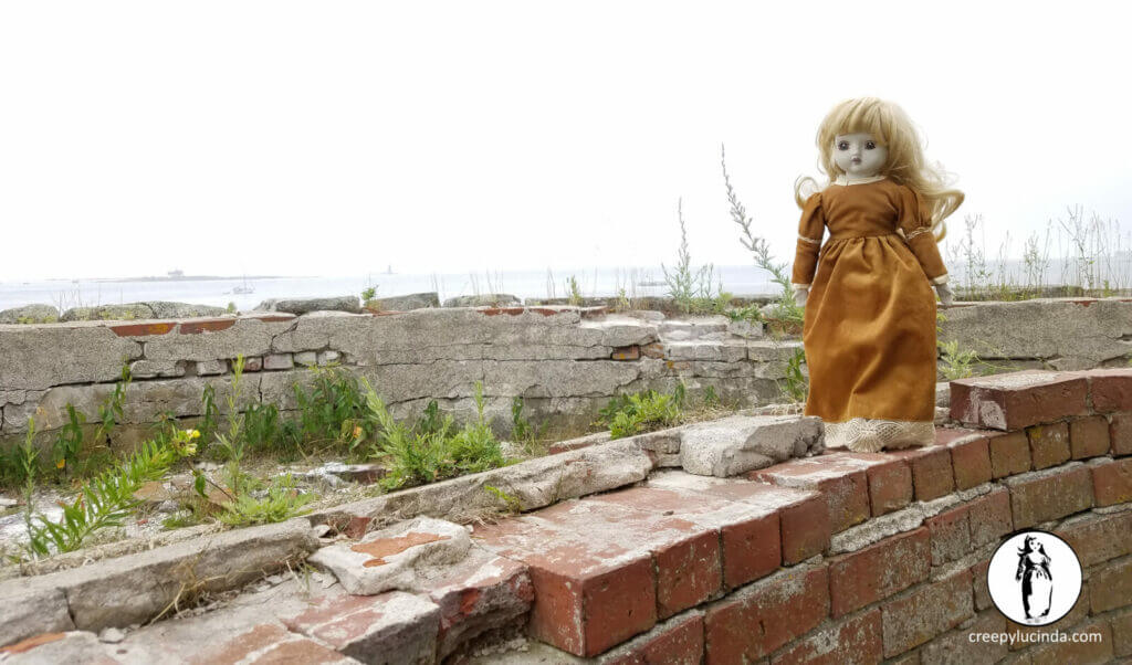Creepy doll standing on a brick wall
