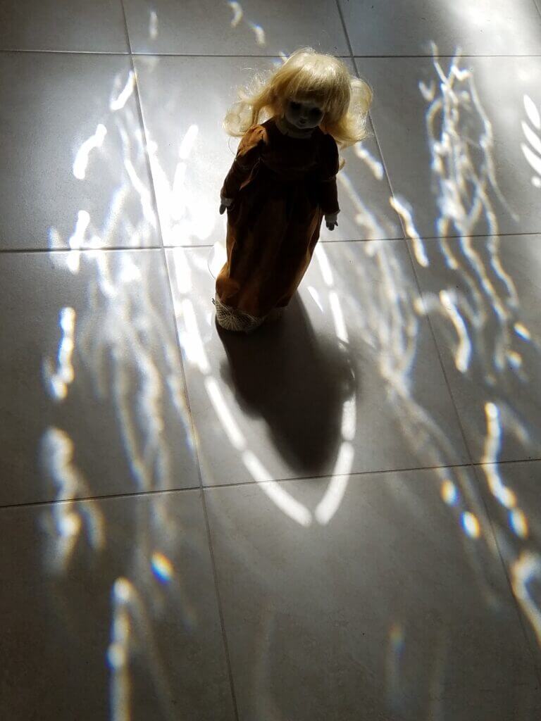 Silhouette of a creepy doll in light and shadow