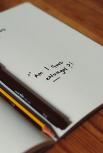 A journal with the words "am I good enough?" written in marker