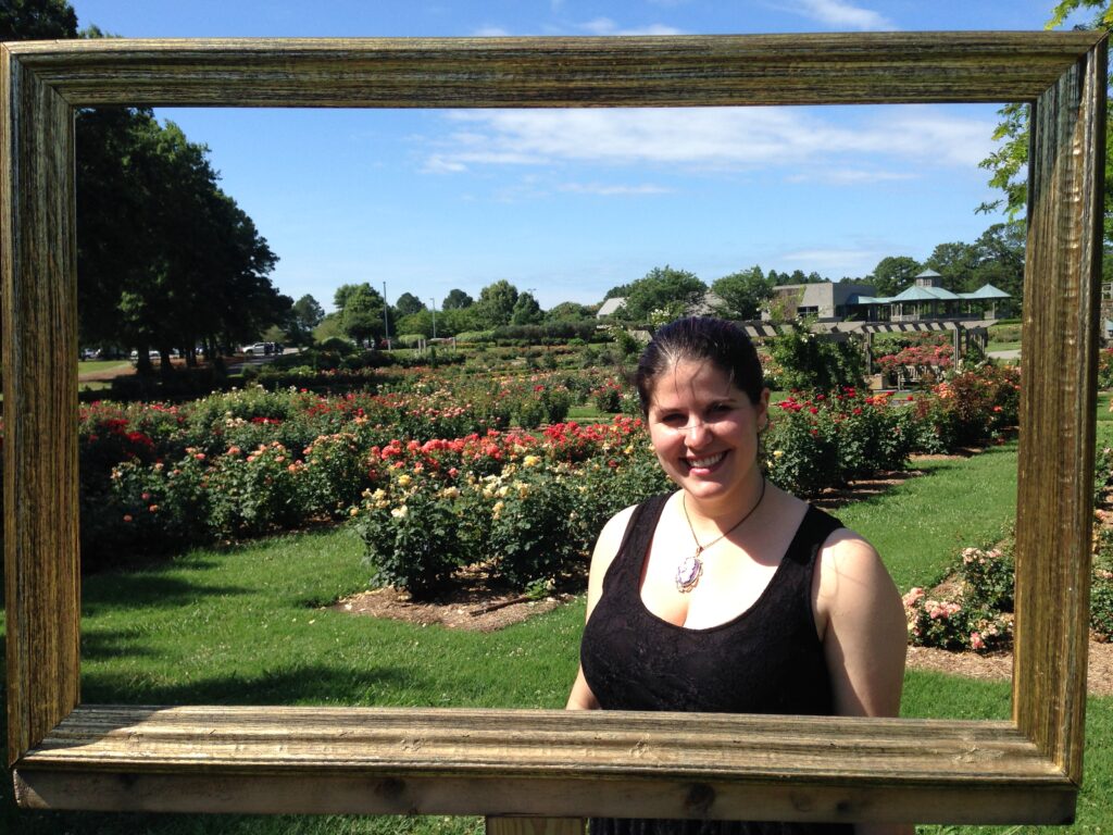 The author posing inside a freestanding frame at a garden
