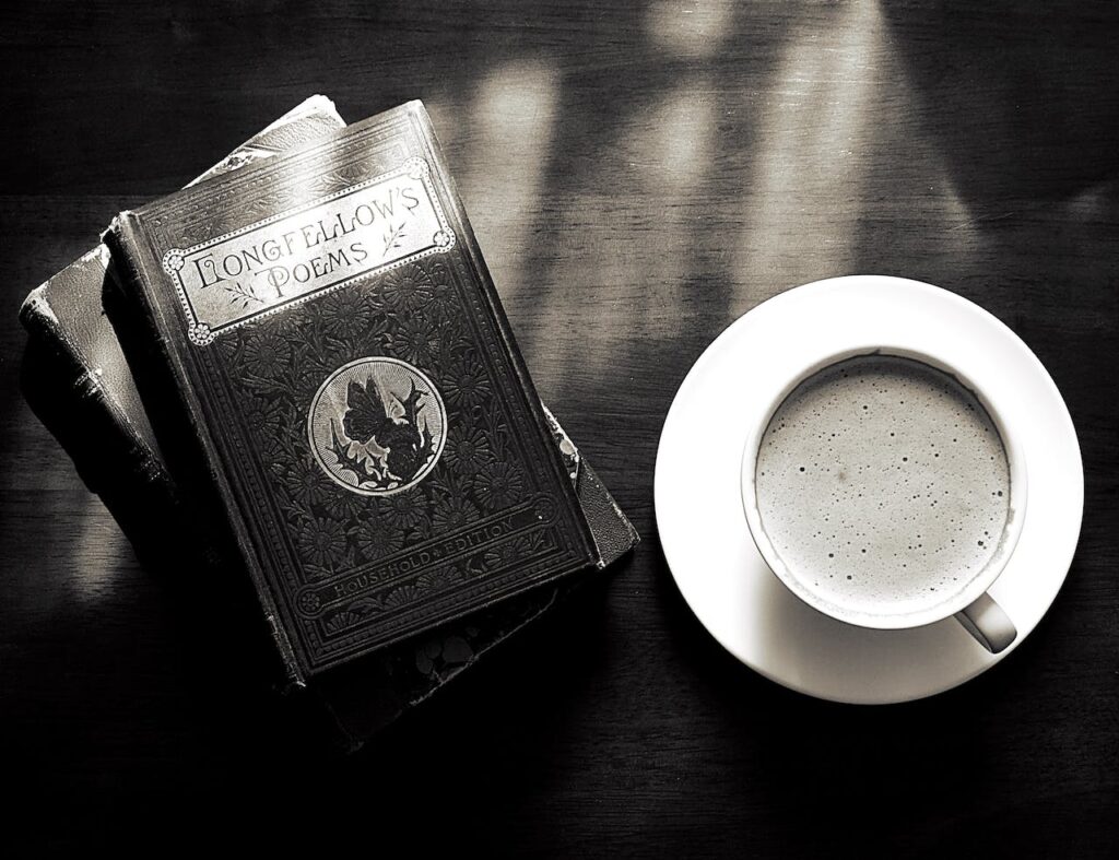 A cup of coffee next to a pile of poetry books